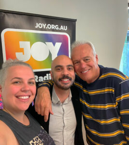 Angelo with Rach and John Deeks in front of JOY banner